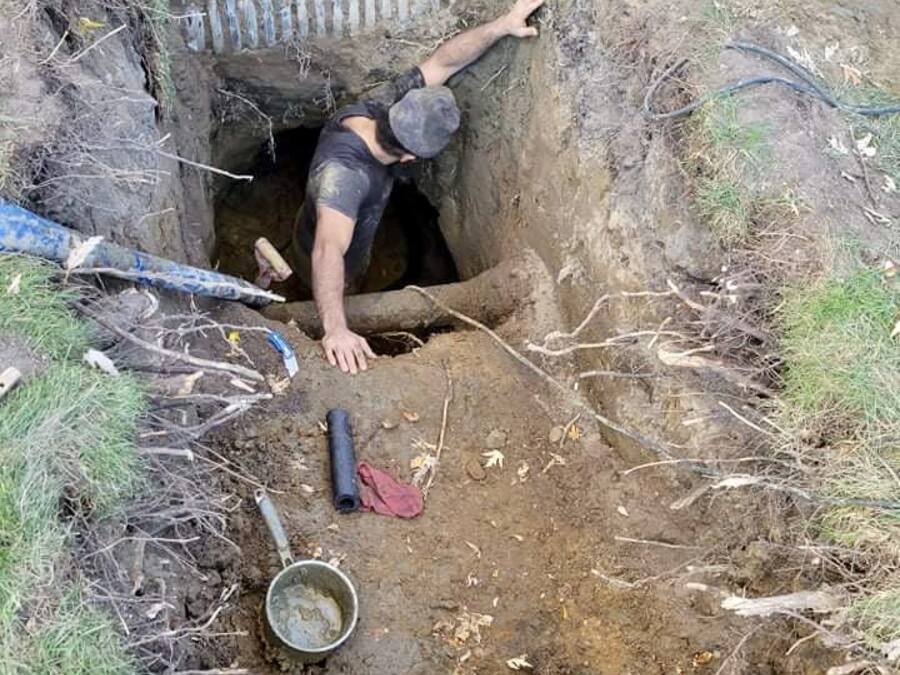 Plumber working in a deep excavation to repair a sewer line